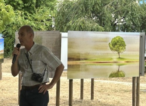 Le photographe Olivier Muhlhoff prenant la parole devant une de ses œuvres photographiques de la série "Arborescence" lors du vernissage du festival de la photo de Moncoutant édition 2026, celle-ci représente un arbre et son reflet devant un lac, celui-ci ayant une forme bien définie, des contours suffisamment marqués et nets, pour les distinguer, alors que le reste de l'image lui, présente un environnement comme flou, cet effet est la résultante, du travail effectué par l'artiste, cet effet porte son nom.